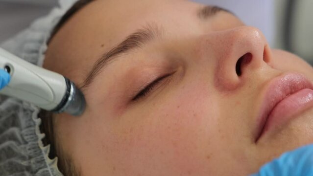Professional moisturizing and rejuvenating hardware procedure. Hydrafacial massage process. Close-up shot of a young woman receiving microdermabrasion therapy at beauty spa.