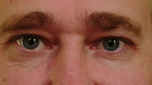 Extreme close-up of an adult smiling man with gray eyes. Expression of emotions through the eyes.