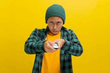 An irritated young Asian man, dressed in a beanie hat and casual shirt, switches TV channels,...