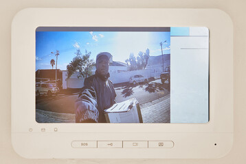 Delivery, security camera and smart home with man courier on screen for ecommerce, distribution or shipping. Display, doorbell or supply chain logistics and African postal worker at entrance with box