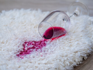 Spilled red wine glass on the white carpet