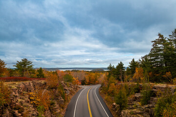 Scenic road along the Acadia National Park, Maine, USA, with the autumn foliage colors and the sea on the background.