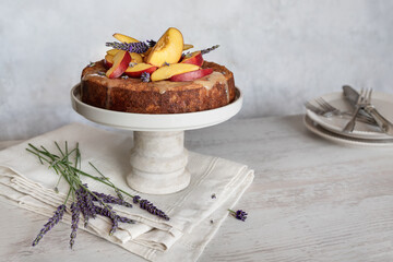 Sponge cake with fresh peach slices and lavender on table