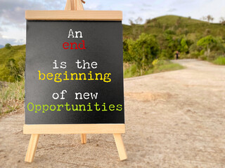 Inspirational motivational quote - an end is the beginning of new opportunities on white board background. Stock photo.