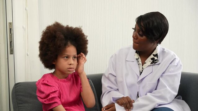 African American psychologist talking with little girl on sofa  in office