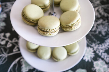 Detail of a candy table. A white porcelain dish with typical French macarons in green color