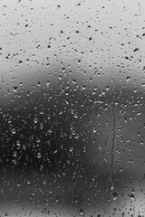 Rain drops on window glass closeup macro. Black and white abstract background texture 