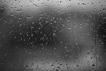 Rain drops on window glass closeup macro. Black and white abstract background texture with rain drop