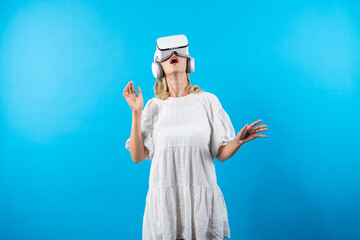 Girl smells flower while wearing VR glasses at blue background. Happy woman with VR goggle enjoy...