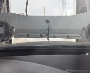 Automatic car wash in the city. Close-up of car washing process. The car is preparing to go to a paid car wash. High quality photo.