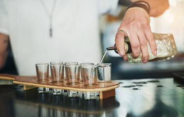 Hands, shot glasses and bartender pouring for order, service and alcohol at social lounge in...