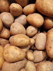 Background of raw natural unpeeled potatoes. Close up of bulk potatoes. Healthy and energetic eating. Fresh organic young potatoes sold on market. Raw vegetables pattern