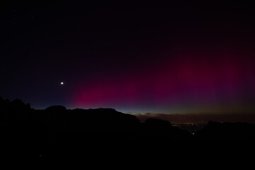 Aurora borealis in Apenzell, Switzerland. Green and red northern lights above mountains. Night sky...