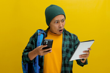 Asian student, dressed in a beanie hat and casual shirt and carrying a backpack, looks shocked while checking his phone, possibly realizing a deadline or schedule mishap, as he holds a notebook
