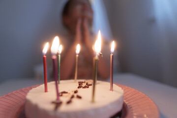 Happy child looks at a cake with candles. girl makes wishes, dreams or prays. celebrates birthday.