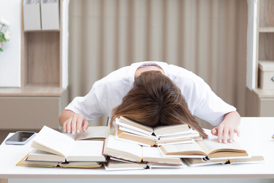 Shocked girl looking at many opened books and stressing for exams. Home education and preparation for examination concept