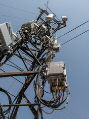 Detailed view of a cluttered utility pole, featuring an assortment of electronic equipment,...
