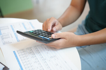 Businesswoman Accountant analyzing investment charts Invoice and pressing calculator buttons over...