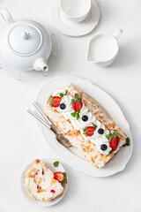 Meringue pavlova roll with mascarpone cream, fresh strawberries and blueberries