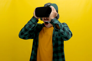 Terrified Asian man wearing a VR headset screams in fear while experiencing a horror movie in VR....