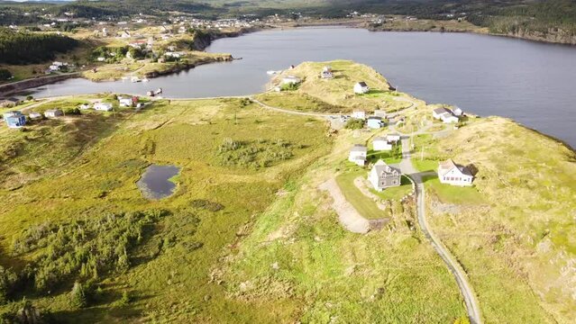 Aerial fly down Newfoundland village with peninsula and small homes overlooking Atlantic Canada.
