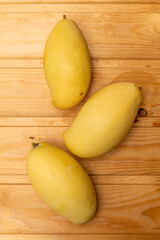 Stack of ripe mangoes fruit on wooden table with green nature at farm