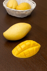 Mango. Close up of fresh ripe mango fruit with leaves over dark wooden table background with green leaves