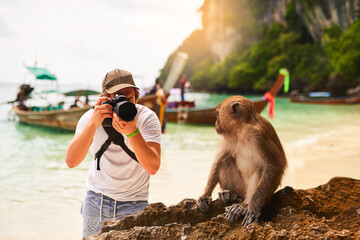 Man, camera and monkey with vacation, beach and tropical island with getaway trip, Bali and travel. Person, photographer and tourist with sunshine, seaside and memory with wild animal and holiday