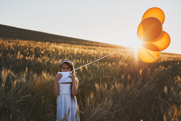 Child, balloons and portrait in field outdoor for communication, letter and message to the sky for fantasy with mockup. Girl, kid and paper in cornfield with travel, innocent and post with sunlight