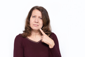 Portrait of a woman on a light background with a swollen cheek, she points a finger on her cheek, a woman has a wisdom tooth and is in pain