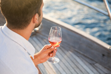 Man drinking wine on yacht at sea. Travel lifestyle in summer vacation, picnic at sunset. Happy...