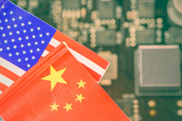 Flags of USA and China fly over a motherboard containing a processor, CPU chip. A semiconductor war...