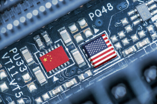 Flag of USA and China on a processor, CPU or GPU microchip on a motherboard. US companies have become the latest collateral damage in US - China tech war. US limits, restricts AI chips sales to China.