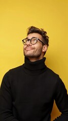 Obraz premium A man in a black sweater and glasses is looking up at the camera with a smile on his face