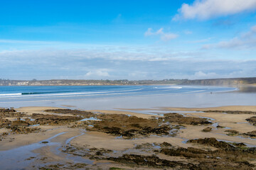 Des sillons rocheux parsèment la plage de sable de la presqu'île de Crozon, tandis que les falaises fournissent un fond spectaculaire, créant une scène côtière à couper le souffle.