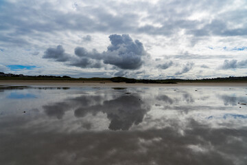 Obraz premium Reflets de gros nuages gris menaçants sur le sable mouillé d'une plage de la presqu'île de Crozon, une atmosphère saisissante et chargée d'émotion.