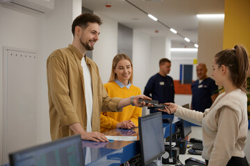 Obraz premium Young couple paying for doctor appointment at clinic reception using smartphone