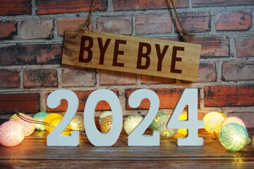 Bye Bye 2024 years number with LED cotton balls decoration top view on wooden background