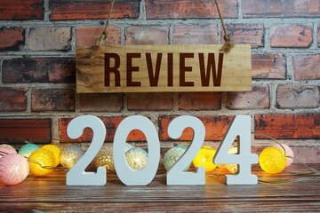 Review 2024 years number with LED cotton balls decoration top view on wooden background