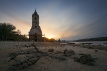 Submerged church of Villanueva de las Rozas, Cantabria in the Ebro reservoir with strong drought due to climate change at sunset © patxi