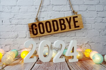 Goodbye 2024 years number with LED cotton balls decoration on wooden background
