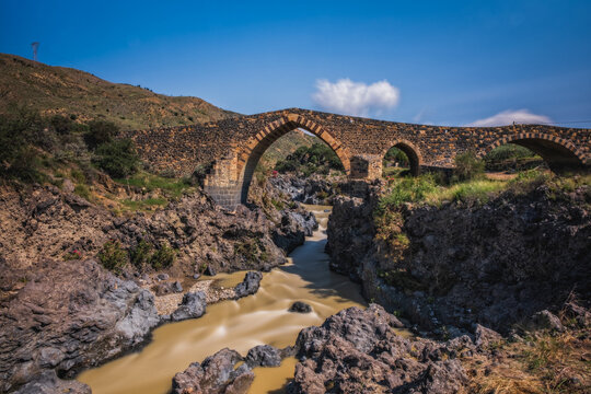 Ponte dei Saraceni. An ancient medieval bridge of Norman age located on the Simeto river. Adrano - Catania, in Sicily. Long exposure picture. June 2023