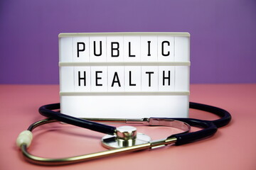 Public Health letterboard text on LED Lightbox and stethoscope on pink and purple background