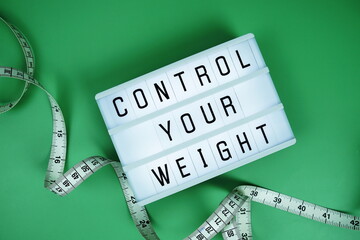 Control Your Weight letterboard text on LED Lightbox and Measuring tape on green background, Healthcare concept