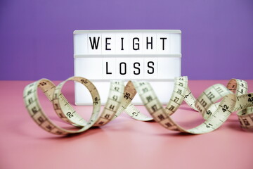 Weight Loss letterboard text on LED Lightbox and Measuring tape on pink and purple background, Healthcare concept