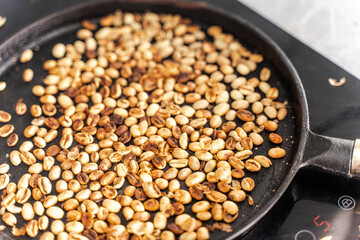 Medium roasted coffee beans are smoky in a roasting pan. Selected focus.