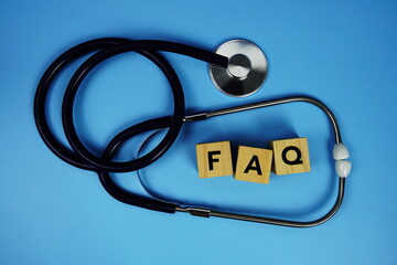 FAQ with wooden blocks alphabet letters and stethoscope on blue background