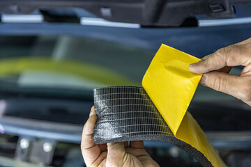 Auto service worker applies soundproof sponge material to the hood of the car, adjusts the sound of...