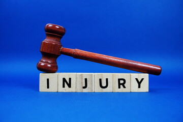 Injury alphabet letters with wooden blocks alphabet letters and Gavel on blue background