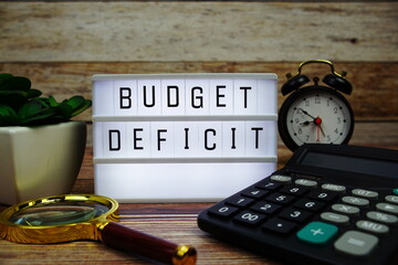 BUDGET DEFICIT letterboard text on LED Lightbox on wooden background, Business and Finance concept...